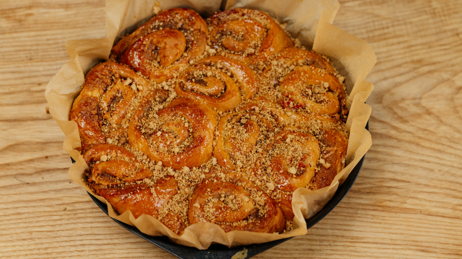 Apple and Ginger Buns in a cast iron pan with parchment paper sticking out the sides