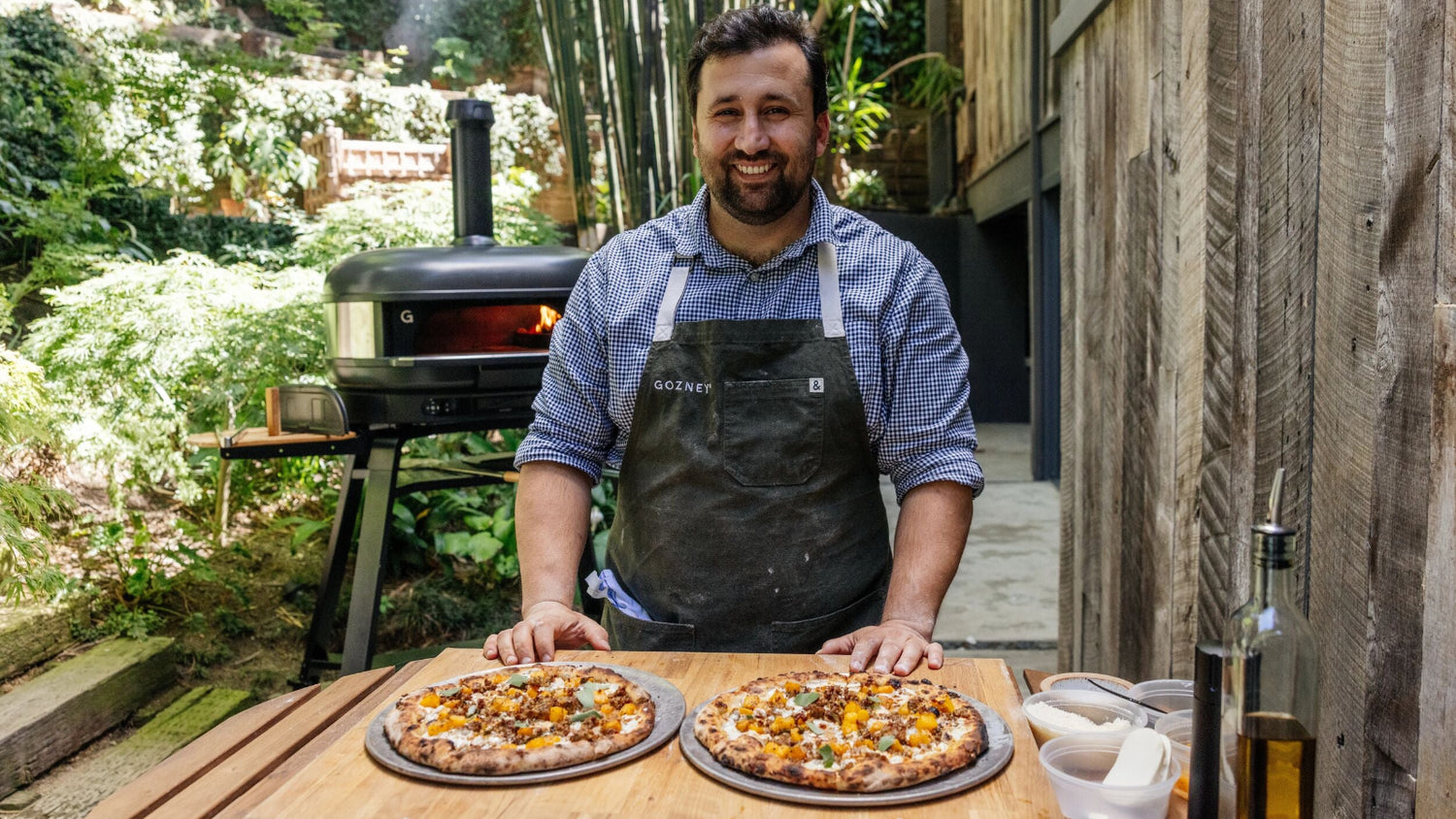Chef Daniele Uditi standing in front of the Gozney Dome (Gen 2) with two pizzas in front of him.