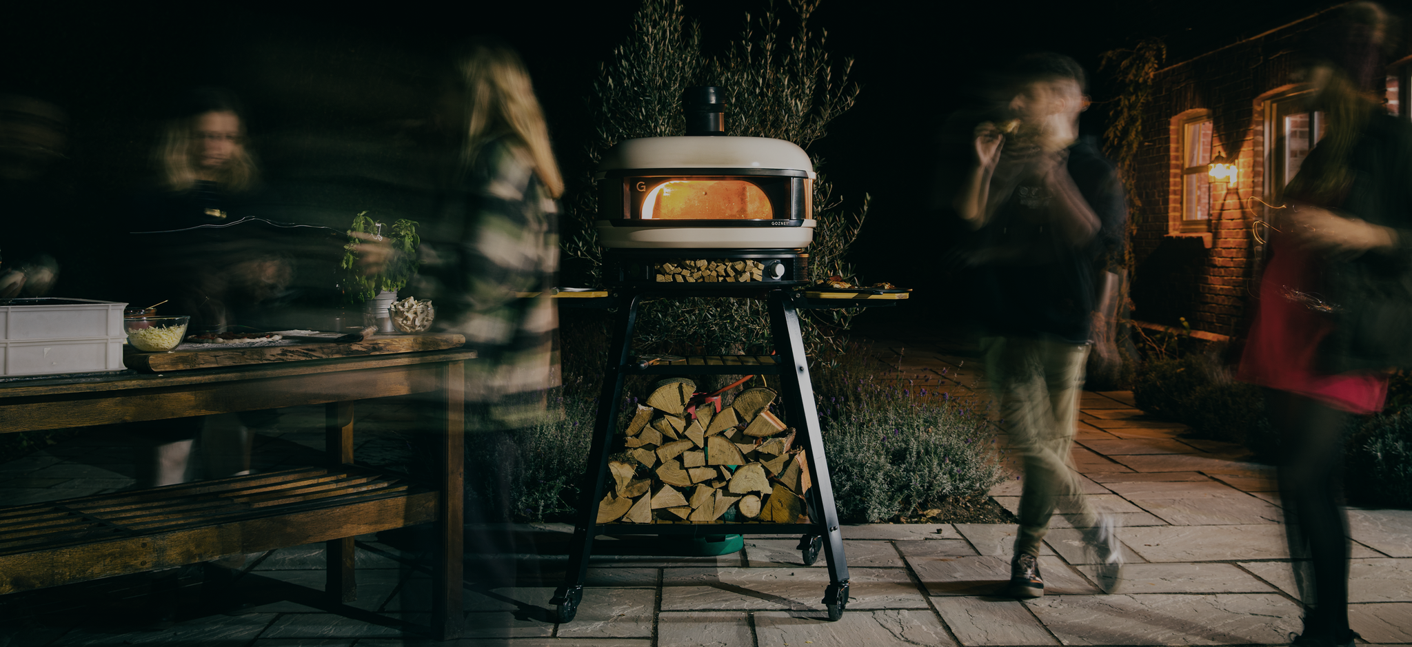 Pizza party at night with lit pizza oven